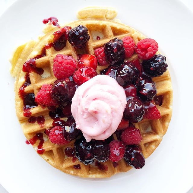 waffle with boysenberry syrup and berry cream cheese on top on a white background.